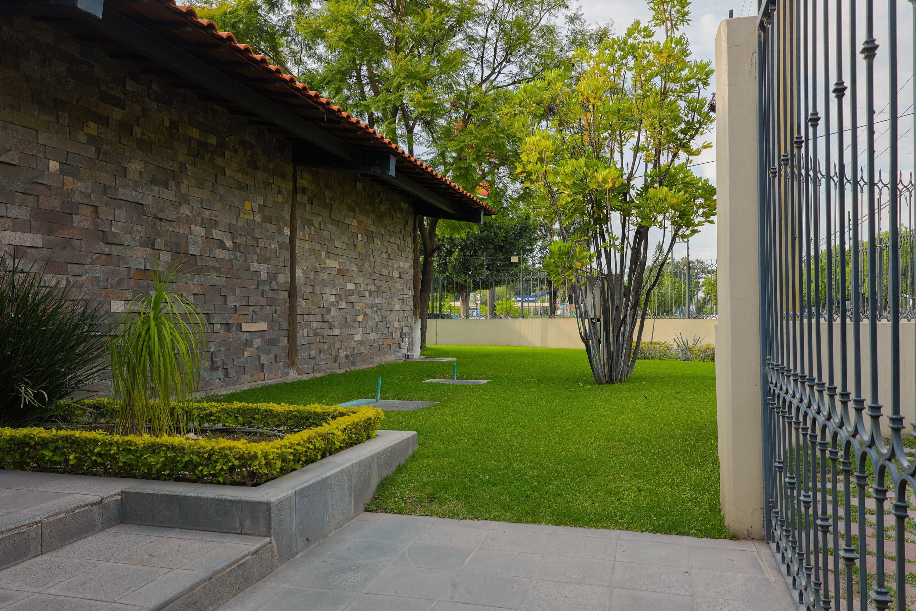Remodelación ASF, vista exterior del jardín y muro de piedra.