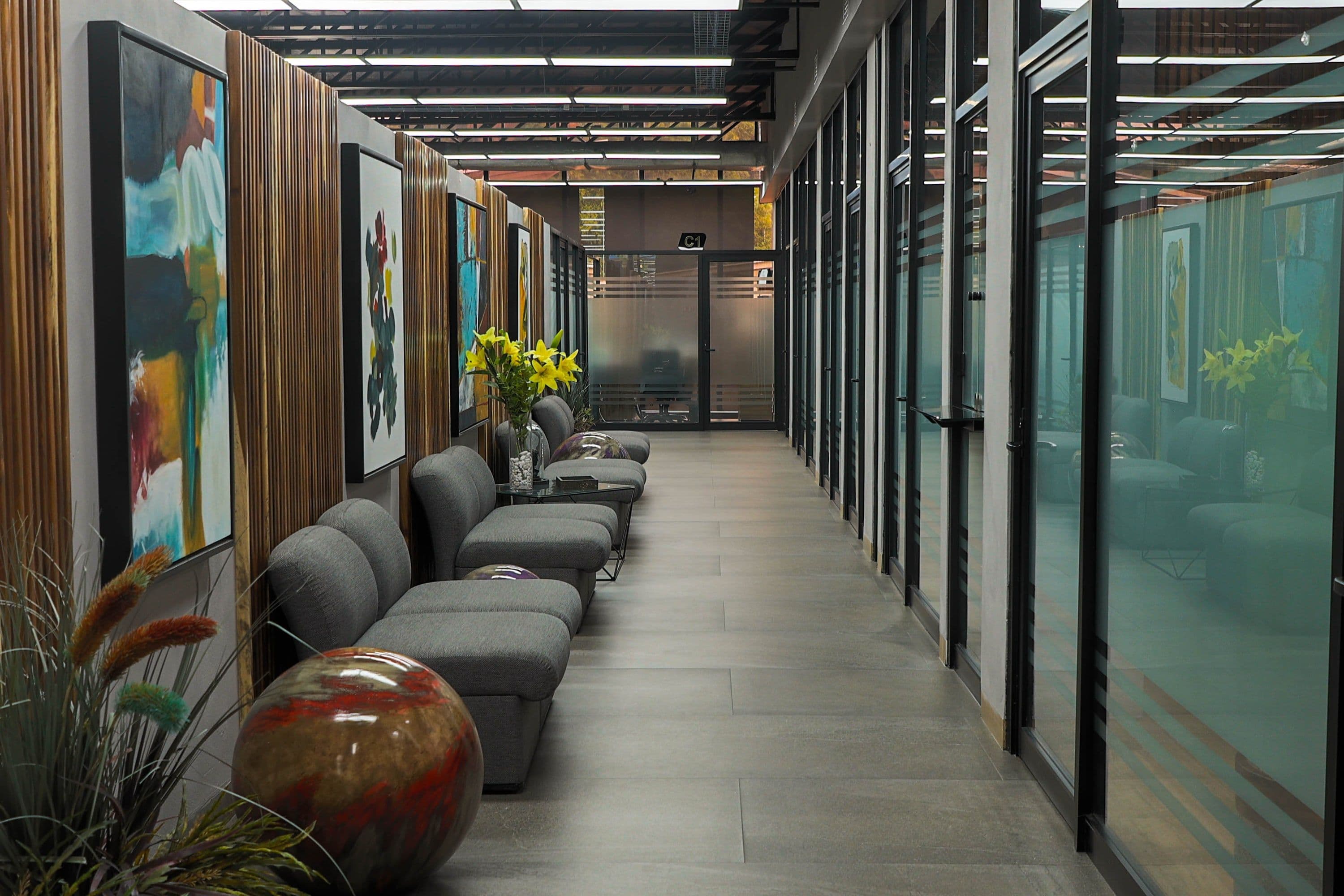 Remodelación GA, corredor de oficinas con paneles de madera, obra gráfica y salas acristaladas.