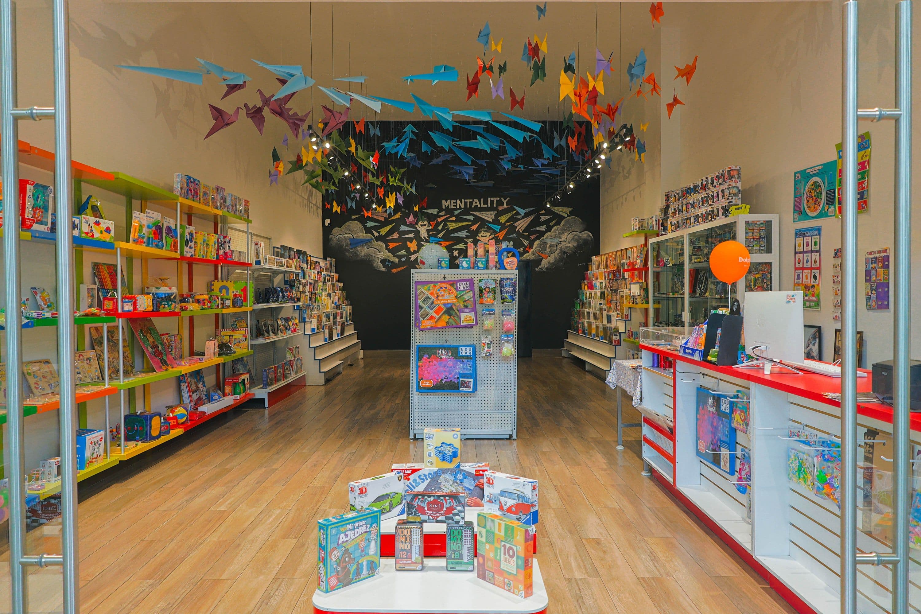 Mentality, vista interior de la tienda con anaqueles y mural de aviones de papel.